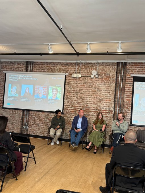 A panel discussion at Groundwork titled "Overture 2.0: What Should Universities Teach About the Future of Finance?" features four speakers seated on a stage in front of exposed brick walls, with NYU's sponsorship visible on the projection screen. The accompanying quote from Professor Gregory Johnson at NYU directly relates to the event's theme, suggesting that cryptocurrency as a distinct category will merge into traditional financial services within five years—reflecting the panel's focus on the future evolution of finance education.