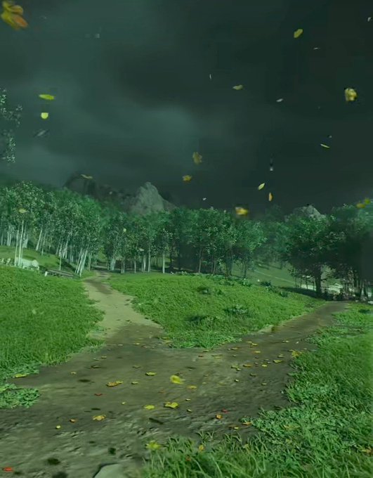 A scenic landscape view showing a dirt path through a grassy field with trees, mountains in the distance, and yellow leaves blowing in the wind under a dark cloudy sky.