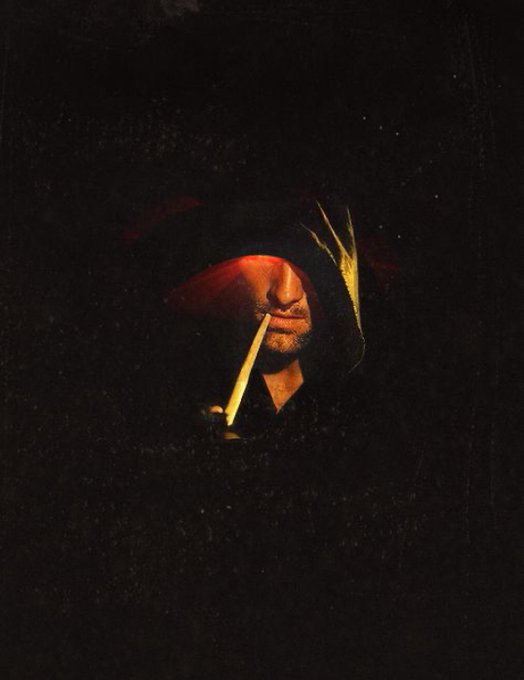 A hooded figure with a hidden face is illuminated by the warm glow of a Bitcoin symbol, embodying the anonymous yet illuminating nature of cryptocurrency. The image visually reinforces the post's message of saving in Bitcoin while focusing on one's craft, with the glowing crypto symbol serving as a guiding light in the surrounding darkness.