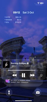 An iOS lock screen showing the time 09:12, date Sat 3 Oct, and a music widget playing 'Burning Bridges' by 'Lakokim & Corey Arcangioli' with a background image of the Roman Colosseum.