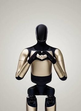 A sleek humanoid robot with gold and black panels stands with its hands forming a heart shape against its chest.