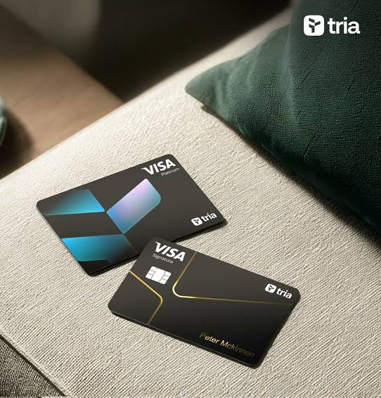 The image features two black Visa cards placed next to each other, with a green pillow visible behind them. The text "@useTria" appears near the bottom of the image. This suggests that the focus of the image might be on promoting the use of these cards or highlighting the benefits of using them for transactions.