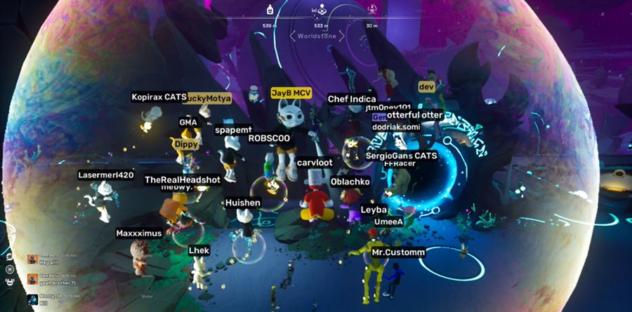 A screenshot from a video game or virtual world shows numerous player avatars gathered on "Worlds One" in a dark, space-themed environment, with names like "JayB MCV" highlighted.