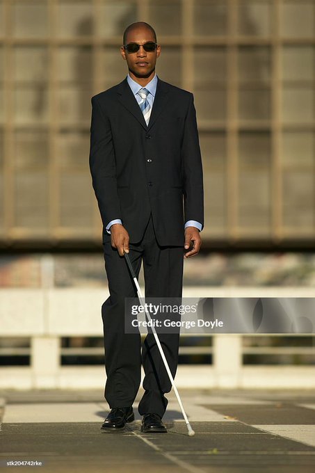 The image shows a man in a dark business suit, light blue striped shirt, and patterned tie, standing on a crosswalk while holding a white cane and wearing sunglasses, indicating he is visually impaired. The "solana looks great" caption appears to be a play on words, possibly referencing the Solana cryptocurrency/blockchain platform rather than a person named Solana, with the image serving as a stock photo that doesn't directly relate to the cryptocurrency's market performance or technology.