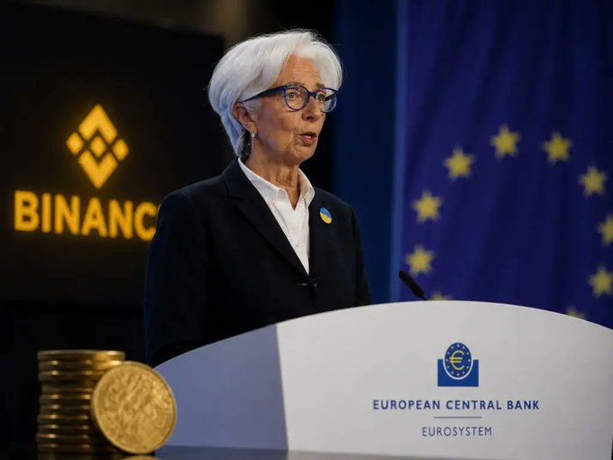 The image shows a woman standing at a podium, giving a speech or presentation. She appears to be wearing glasses and has white hair. In front of her are stacks of gold coins, which could potentially be related to the European Central Bank's approval of Bitcoin. The context suggests that she is addressing an audience about the implications of Europe's Digital Euro and how it might affect Bitcoin and other cryptocurrencies.