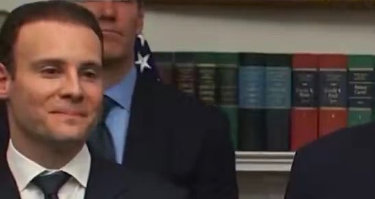 A man in a dark suit and tie smiles slightly at what appears to be a formal event, with another suited figure and an American flag visible in the background. The image shows no connection to the accompanying post about decentralized identifiers and Technocore—it's unrelated visual content paired with text about creating a DID using Flop Labs' platform.