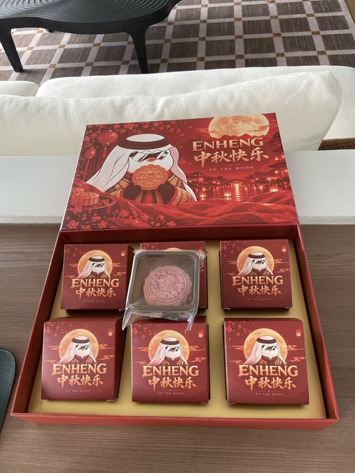 An open red gift box containing individually wrapped mooncakes with a man wearing traditional Arab clothing, labeled 'ENHENG 中秋快乐 TO THE MOON'.
