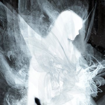 An abstract, smoky grayscale composition featuring flowing, ethereal forms that resemble swirling mist or fabric against a dark background.