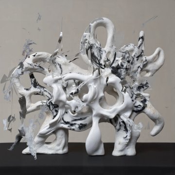 A chaotic white abstract sculpture made of twisted, tendril-like forms covered in black and blue paint splatters.
