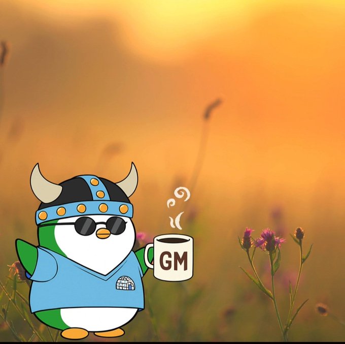 A cartoon penguin wearing a Viking helmet and sunglasses holds a steaming coffee mug labeled "GM" against a golden sunset field of wildflowers, perfectly capturing the cheerful "GM — Happy Tuesday!" greeting with its cozy morning-vibes aesthetic.