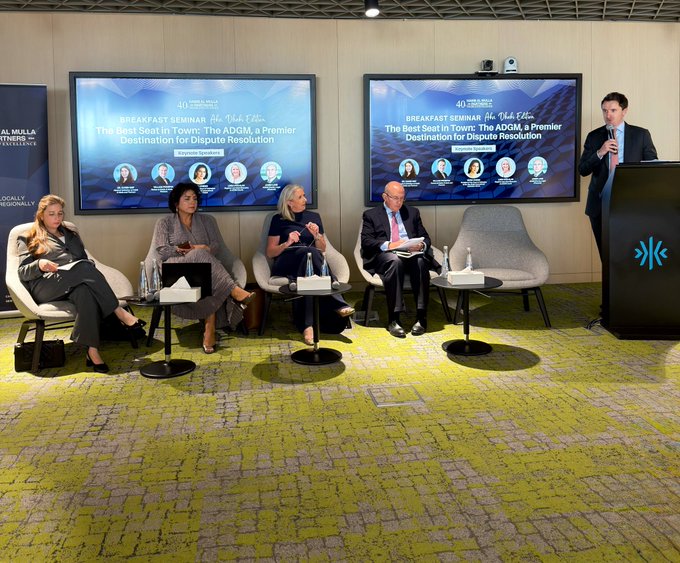 A panel discussion titled 'Breakfast Seminar: The Best Seat In Town: The ADGM, a Premier Destination for Dispute Resolution' featuring four seated speakers and a moderator at a podium, with a sign referencing Mulberry Partners and ADGM.
