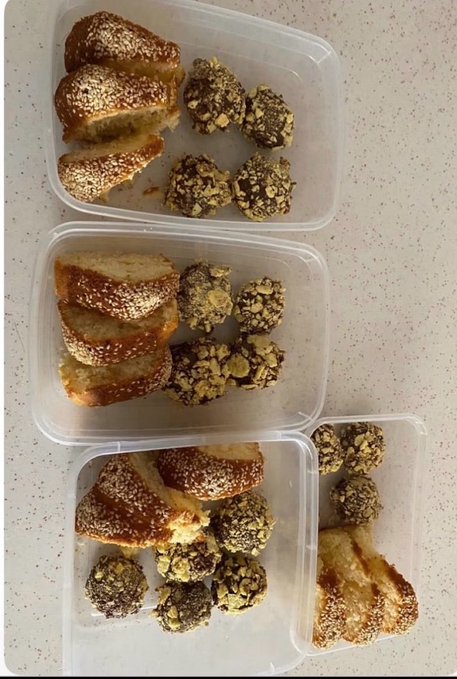 Three plastic containers filled with sliced sesame seed cake and round seed/nut-coated balls arranged on a white speckled countertop.