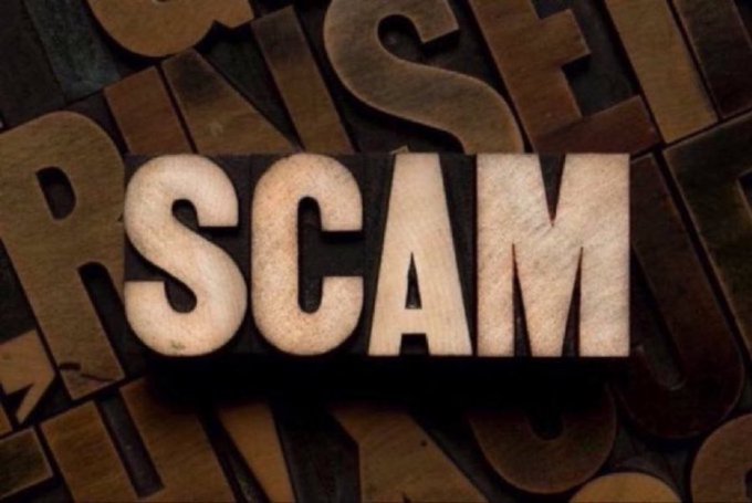 Close-up image of wooden letterpress blocks with the word 'SCAM' prominently displayed in the center.
