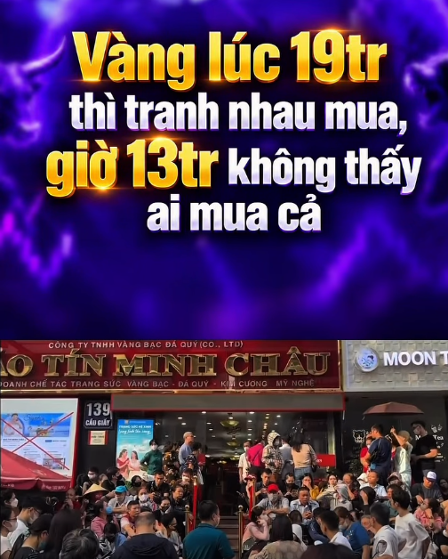A crowd gathers outside a shop with Vietnamese text reading 'AO TÍN MINH CHÂU' under a promotional graphic about gold prices ('Vàng lúc 19tr thị tranh nhau mua, giờ 13tr không thấy ai mua cả').