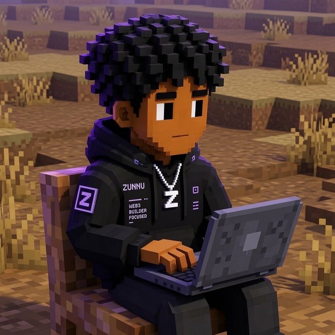A 3D voxel-style illustration of a young man with dark curly hair, wearing a black hoodie with 'ZUNNU' and 'WEB3 BUILDER FOCUSED' text and a 'Z' chain necklace, while working on a laptop in a blocky, desert-like landscape.