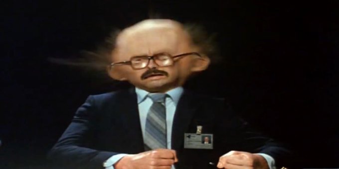 A man in a suit and tie with a press badge sits at a desk, with the image artificially distorted to give him a comically enlarged, misshapen head with glasses and a mustache. The exaggerated, almost cartoonish appearance satirizes the post's criticism of perceived hypocrisy in Bitcoin's policy debates over OP_RETURN size limits.