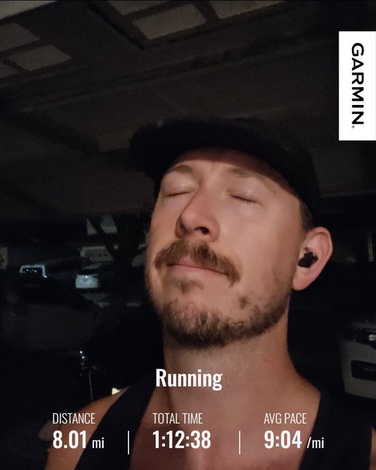A post-workout selfie of a man with closed eyes wearing a black cap and earbuds, with Garmin running stats showing 8.01 mi distance, 1:12:38 total time, and 9:04/mi average pace.