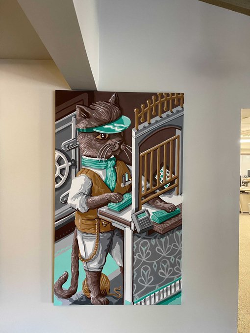 A mural on a wall depicting an anthropomorphic cat working at a teller window, wearing a green visor, a bandana, and a gold chain, handling stacks of money and a cash register.
