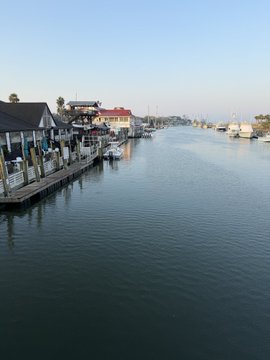 A scenic canal view with waterfront houses, docks, and boats on a clear sunny day.