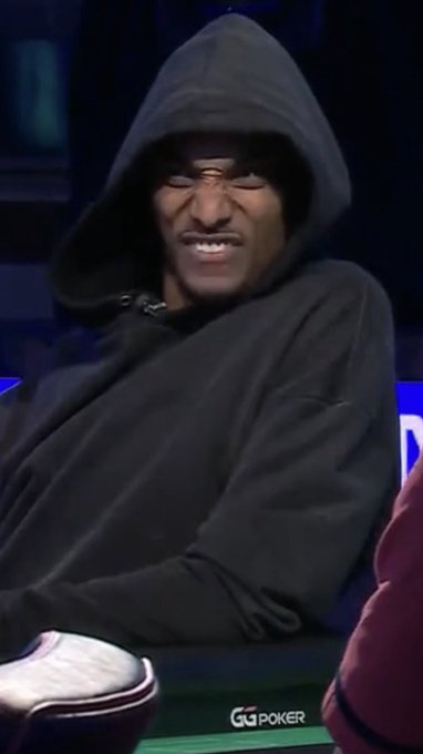 A man in a black hoodie pulls the hood over his face with a grimacing expression during what appears to be a GG Poker broadcast.