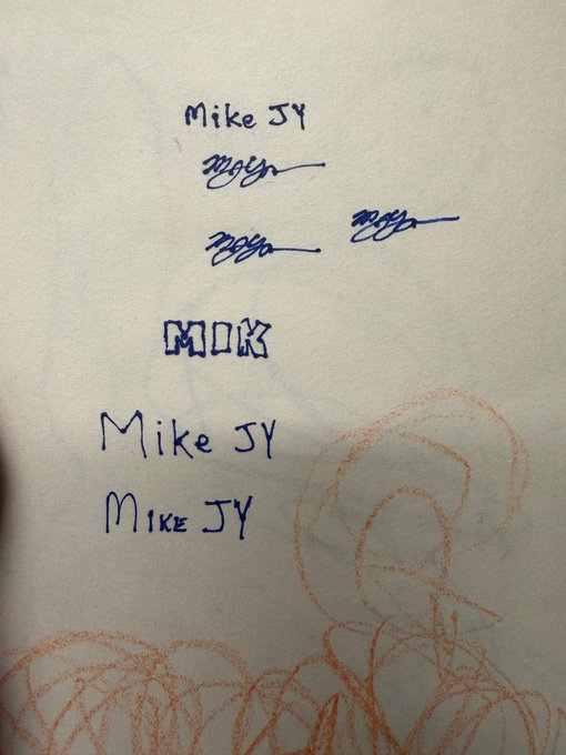 A handwritten note featuring the signature/name 'Mike JY' written multiple times in blue ink, accompanied by abstract scribbles and an orange crayon drawing.