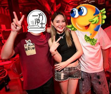 Three people pose together at a Changsha venue celebrating Spain's World Cup victory, with two figures' faces covered by emoji and a "二十分钟" (20 Minutes) sticker, while the smiling woman in the center wearing a black top and denim shorts flashes peace signs alongside her companions.