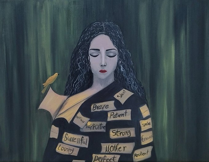 A serene woman with closed eyes and flowing dark hair wears a robe covered in labels of positive affirmations—"Brave," "Strong," "Patient," "Mother," "Successful," "Perfect," and more—while a small yellow bird perches on a scroll at her shoulder. The image powerfully visualizes the idea of carrying self-imposed identities and expectations, inviting viewers to consider the stories we tell about ourselves in a single, evocative moment.