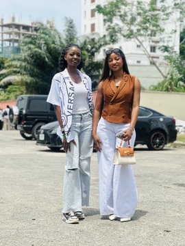 Two stylish women pose together outdoors, with one wearing a white sash reading "IVERSA" across her torso, alongside parked vehicles and greenery in the background. The caption suggests the image captures a memorable moment at a social event where the poster met many wonderful people, with this photo likely featuring one of the tagged individuals (@teddi_speaks or @NFT__NG) or another attendee from the gathering.