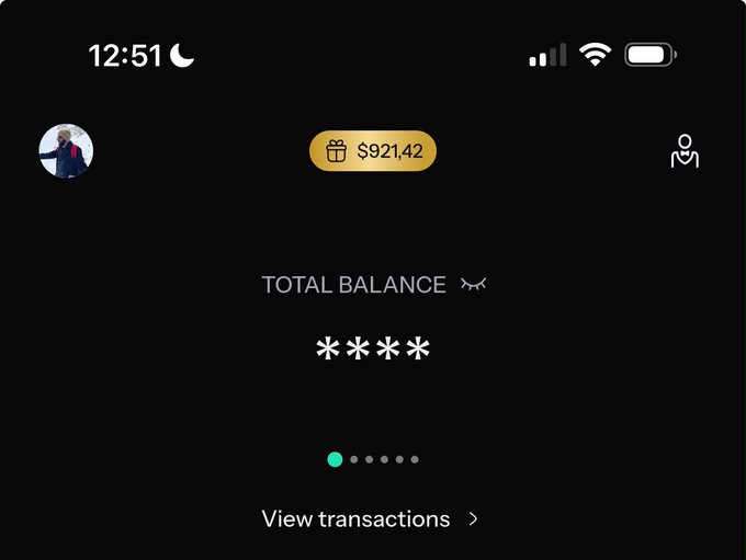 A dark-themed banking app screen showing '12:51', a profile picture, a gift icon with '$921.42', and 'TOTAL BALANCE' masked with asterisks.