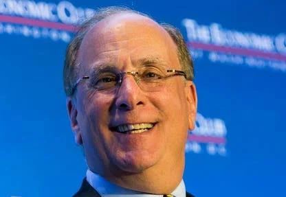 A close-up photograph of economist Larry Black smiling, with 'The Economic Club' branding visible on the blue background behind him.