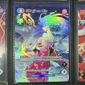 The image shows a holographic Azuki TCG card featuring "Sōryū no Rin" (card number 8), an anime-style character with flowing blue and pink hair holding a mystical spear. The card exemplifies the kind of visually striking artwork that drives Azuki TCG's collector appeal, directly supporting the post's claim that the game has already cultivated a strong collector base thanks to its stunning card designs.