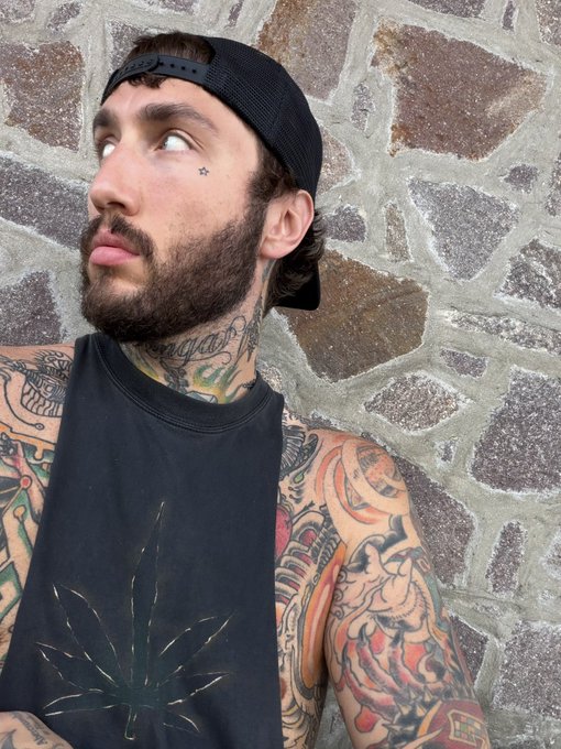 A bearded man with extensive colorful tattoos and a backwards black cap looks off to the side against a stone wall background. The image likely serves as a promotional headshot for streamer "fazebanks" (twitch.tv/fazebanks), who is advertising a livestream event where viewers can win Solana cryptocurrency on Twitch and X.