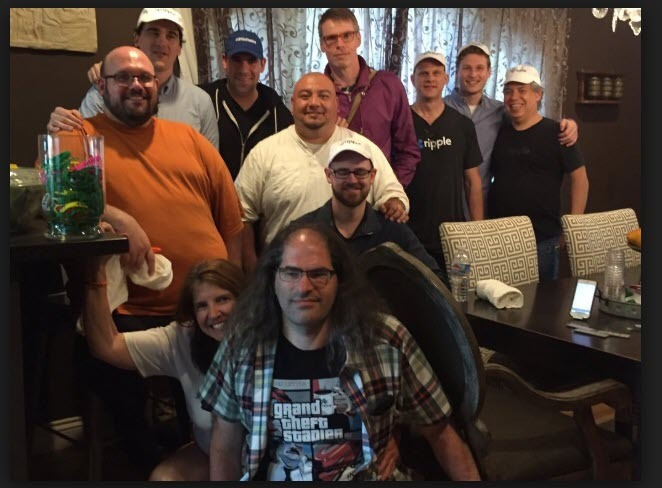 A group photo of people gathered at a dinner table, including a man wearing a "ripple" shirt and another wearing a "grand theft stadium" t-shirt, taken in what appears to be a restaurant setting. The image relates to the post about Ripple co-founder Arthur Britto and the purpose behind XRP, suggesting the photo may capture Britto or other Ripple-related individuals at a social gathering.