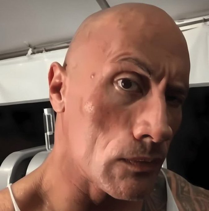 A close-up selfie-style render or photo of a bald man with a stern expression, visible tattoos on his shoulder, in what appears to be a gym or industrial setting.