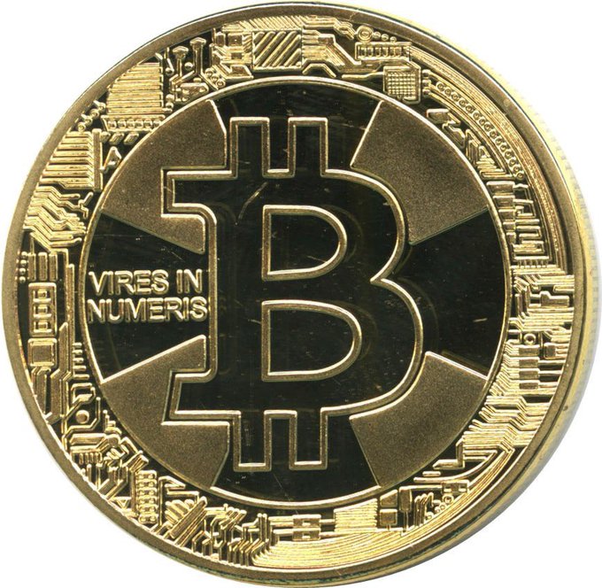 A physical Bitcoin commemorative coin featuring the iconic ₿ symbol with the inscription "VIRES IN NUMERIS" (Latin for "strength in numbers"), surrounded by a circuit board design that ties into the post's theme of Bitcoin's early motto and the decentralized strength derived from a united community of network participants.