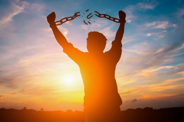 A silhouette of a man breaks free from chains with arms raised triumphantly against a vibrant sunset, symbolizing liberation and empowerment, which complements the post's sentiment about escaping typical Bitcoin-copying volatility and alternatives.
