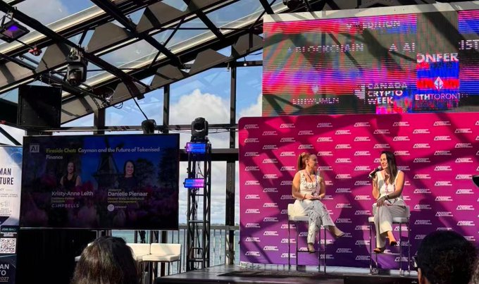 Two women are seated on a stage during a panel discussion at the AI ONFERENCE held at CANADA CRYPTO WEEK, with a screen displaying the session "Franklin Chitt, Grayson and the Future of Tokenized Finance" featuring speakers Kitty-Anne Leith and Daniela Peixoto of Cappfinity. The image relates to the post by showing a scene from a crypto/blockchain conference, which aligns with the article's theme about young people pursuing Web3 careers as an alternative path during a bear market.