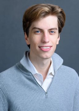 A young man with light brown hair smiles at the camera while wearing a gray quarter-zip sweater over a white collared shirt, posing against a gray background in what appears to be a professional headshot. The caption about "leverage is not your friend" suggests the image accompanies a post about lessons learned from trading losses, with the polished portrait perhaps representing the trader before or after a financial setback.