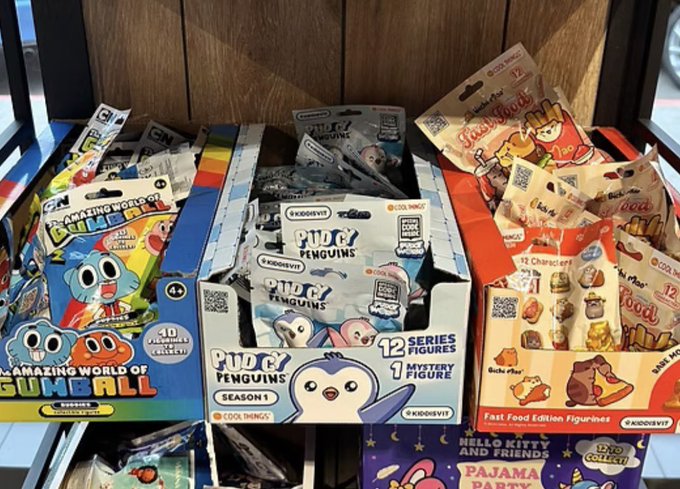 Several boxes of Kidrobot collectible toys are displayed, including 'Amazing World of Gumball', 'Pudgy Penguins Season 1', and 'Fast Food Edition Figurines' featuring Hello Kitty and Friends.