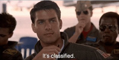 The image shows a man with sunglasses looking at another person who has his hand over his mouth. The caption reads "It's classified," which seems unrelated to the scene. However, there are two people sitting behind them, one of whom appears to be wearing a military uniform and is holding a gun. This adds an element of danger or conflict to the image that contrasts with the man in sunglasses looking at someone else.