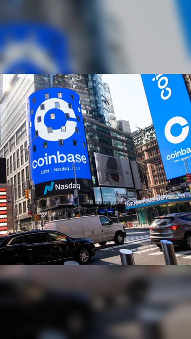 A Times Square street scene shows large blue Coinbase and Nasdaq signs with the Nasdaq market ticker and the Nasdaq building marquee visible among traffic and tall buildings.