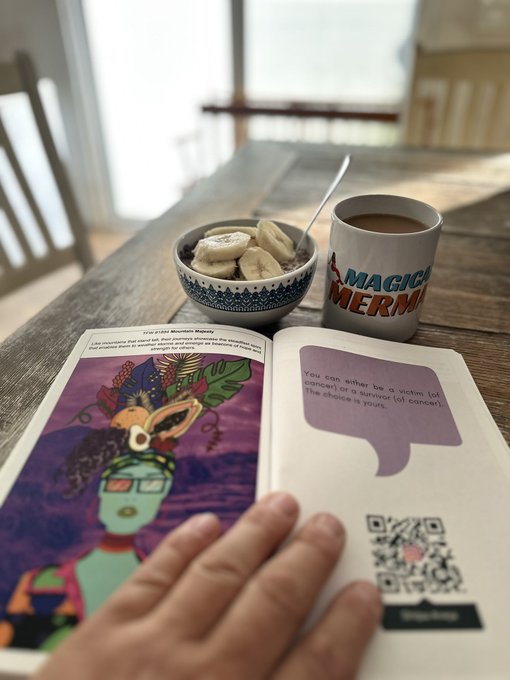 A cozy breakfast scene with an open illustrated book, a bowl of oatmeal with banana slices, and a mug reading 'MAGICAL MERMAID' on a wooden table.