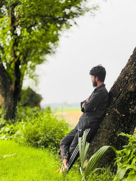 iced tea on a table, with a man leaning against it and trees in the background.