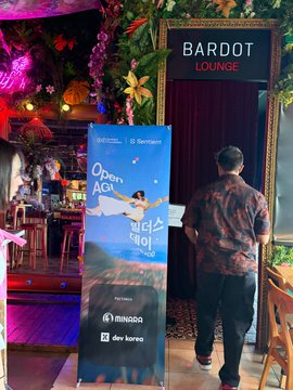 A person in a patterned shirt standing at the entrance of 'Bardot Lounge', looking at a promotional banner for 'Open AGI' featuring speakers from NIMOS and dev bureau.