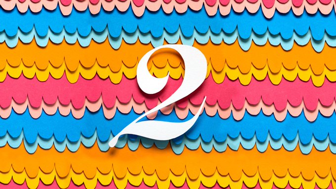 A decorative graphic featuring a large white number '2' set against a layered, scalloped background in shades of blue, pink, orange, and yellow.