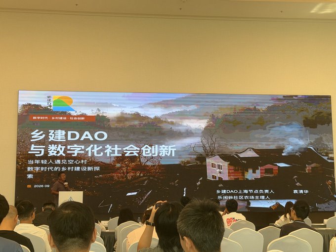 A conference presentation titled '乡建DAO 与数字化社会创新' (Rural DAO and Digital Society Innovation) is shown on a large screen with a speaker presenting to an audience.