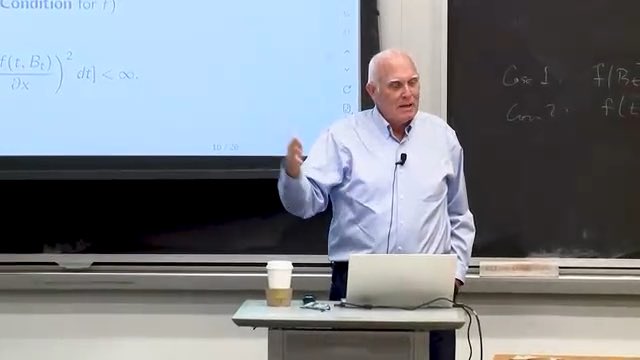 A distinguished MIT mathematics professor delivers a lecture, gesturing toward a screen displaying the mathematical condition "∂(f_t, B_t)/∂x)² dt) < ∞," which represents the foundational stochastic calculus formula underlying modern financial derivatives pricing.