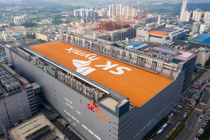 An aerial view of a large SK hynix semiconductor fabrication facility with an orange rooftop displaying the company logo.