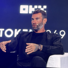 A bearded man speaks on stage at the OKX Token2049 Singapore 2025 conference, gesturing with his hands as he discusses the upcoming launch of the WLFI app by World Liberty Financial.