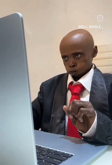 A meme photo of a man in a suit with a red tie pointing at a laptop screen with a serious expression, watermarked '@KOLU_WAHALA_' on Instagram.